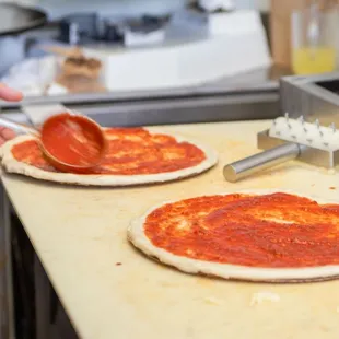 two uncooked pizzas