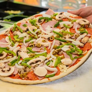 a person putting toppings on a pizza