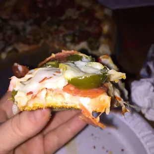 a hand holding a slice of pizza