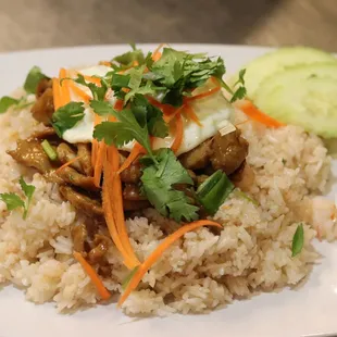 Khao Koung Kapi- shrimp-based fried rice topped with sweet pork and egg over easy. Garnished with green onions, carrots and cucumbers.