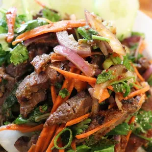 Yum Nua- Our most popular grilled steak salad grilled and tossed with carrots, cilantro, red onions and topped on a bed of lettuce