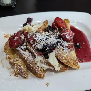a plate of french toast with berries and powdered sugar
