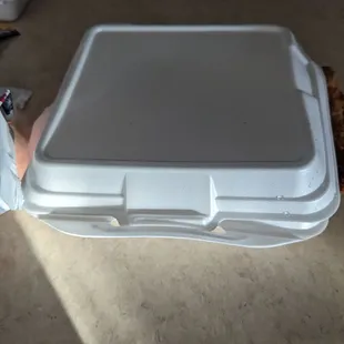a white takeout container with a sandwich in it