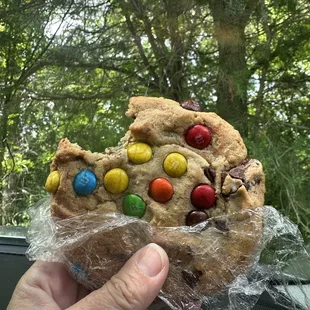 a person holding a cookie with m &amp; m's on it