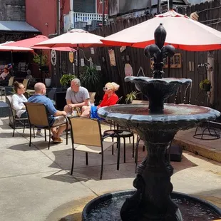a fountain in a courtyard with tables and umbrellas