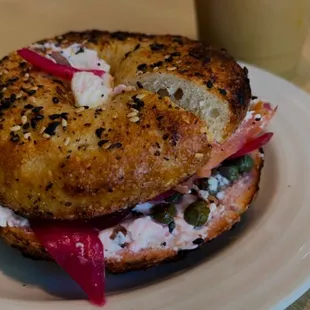 a bagel sandwich on a plate with a drink