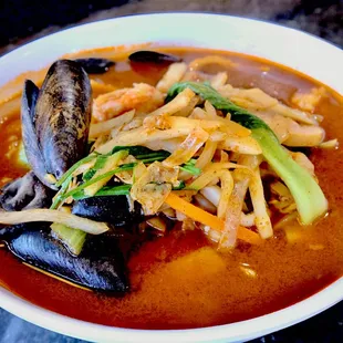 a bowl of soup with mussels and other vegetables