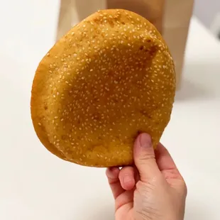 a hand holding a sesame bun