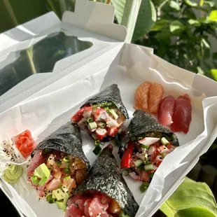 a hand holding a box of sushi