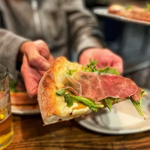 Pizza with lemon béchamel sauce, arugula, fuyu persimmon and prosciutto