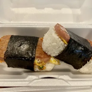 two sushi rolls in a styrofoam container
