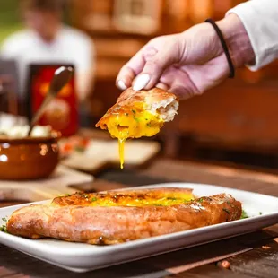 a person dipping a piece of bread into a bowl of soup