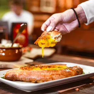 a person dipping a piece of bread into a hot dog