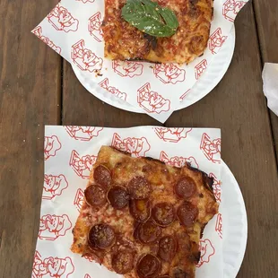 two slices of pizza on paper plates