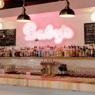 a bar with stools and a neon sign