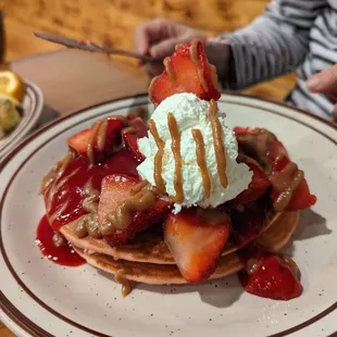 a stack of pancakes with whipped cream and strawberries