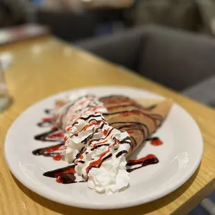 Crepe filled with apple compote and topped with whipped cream, raspberry, chocolate and Nutella drizzle for dessert!