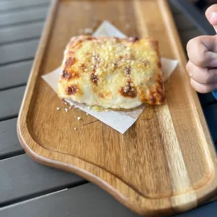 a slice of cheese pizza on a cutting board