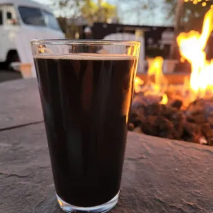 a glass of beer on a table with a camper van in the background