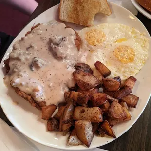 Chicken fried steak with eggs .