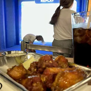 a tray of chicken wings and a glass of soda