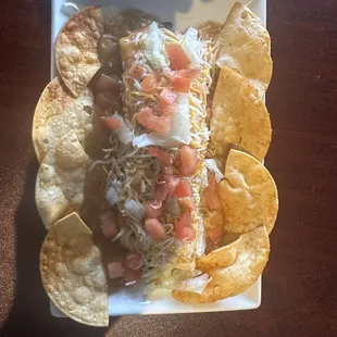 A Smothered Burrito with homemade chips, smothered in Green Chile, Cheese &amp; tomatoes.