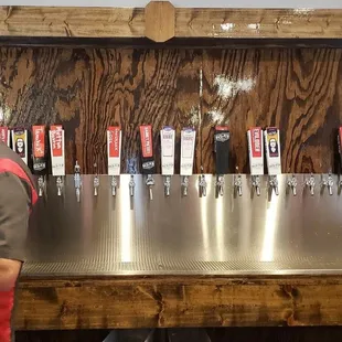 a man standing in front of a row of beer taps