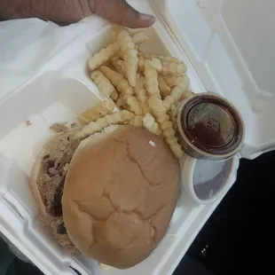 Large pulled pork sandwich with baked beans and fries.