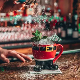 a person pouring a drink into a santa mug