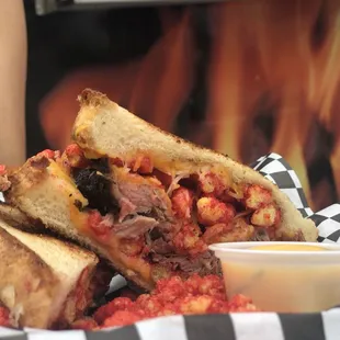 a grilled meat sandwich with a side of sauce