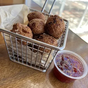 a basket of fried donuts with a side of jam
