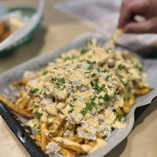 a tray of french fries with cheese and parsley
