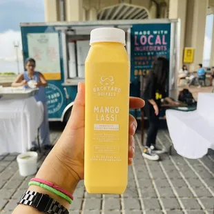 a hand holding a bottle of mango juice