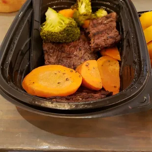 a meal in a plastic container with carrots and broccoli