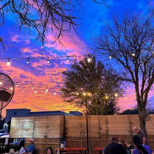 people sitting at picnic tables under string lights