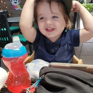 a little boy sitting at a table with a hat on his head