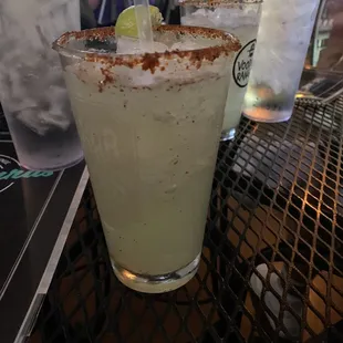 a glass of margarita with a lime slice on the rim