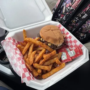 a hamburger and fries in a styrofoam container