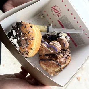 a hand holding a box of donuts