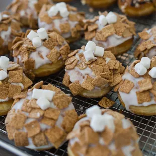 a tray of donuts with frosting and marshmallows