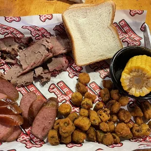 Two meat combo plate to include: sliced brisket, sausage, fried okra, and corn on the cob.