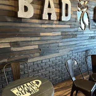 tables and chairs in front of a wood wall