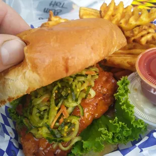 a hand holding a sandwich and french fries