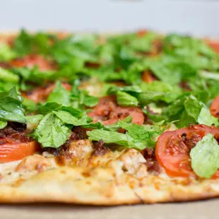 a pizza with tomatoes and lettuce