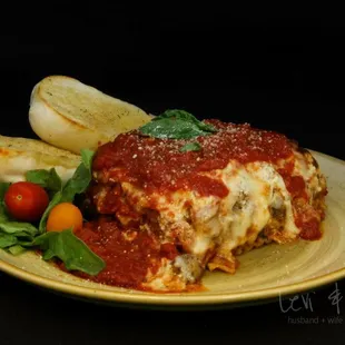 a plate of lasagna with a side of potatoes