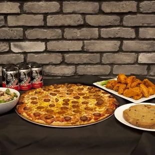 a pizza, salad, and beer on a table