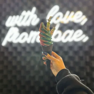 a person holding an ice cream cone in front of a neon sign