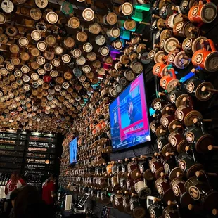 a bar with a lot of beer kegs hanging from the ceiling
