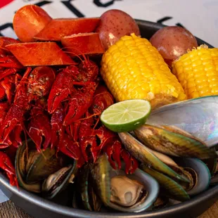 a bowl of lobster, corn and potatoes