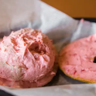 two pink frosted donuts in a basket